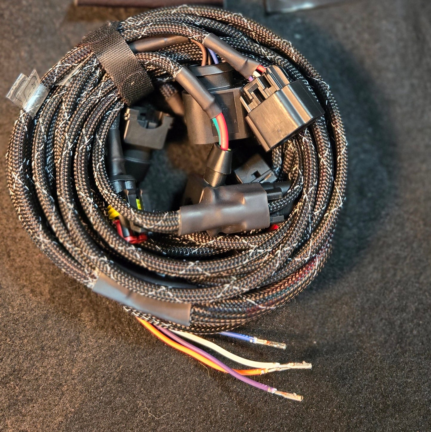 Wound cable with connectors on a black surface, next to a black box with a logo.